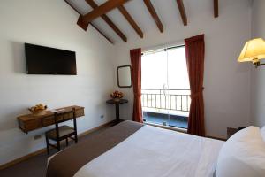 a bedroom with a bed and a desk and a window at DM Hoteles Cusco in Cusco