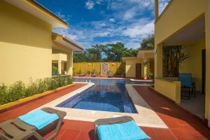 a swimming pool in a house with two chairs and a swimming pool at Tamarindo Garden Boutique Homes in Tamarindo