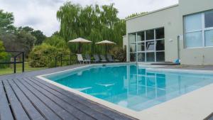 a swimming pool with a wooden deck next to a house at Brisas Serranas in Tandil