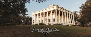 a white building with columns on top of a field at Greenwood Plantation B&B Inn in Saint Francisville