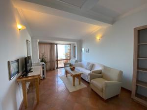 a living room with a white couch and a tv at Apartments and Rooms Levantin Inn in Sveti Stefan