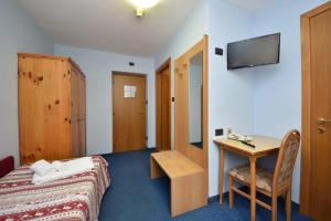 a hotel room with a bed and a desk and a television at Hotel Villa Agomer in Canazei