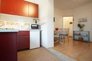 a kitchen with red cabinets and a kitchen with a table at Guest House Marković 279 in Rovinjsko Selo