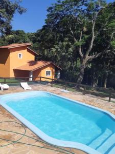 a swimming pool with a house in the background at Chácara Barros in Águas da Prata