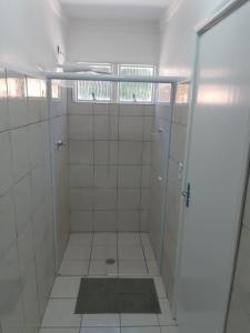 a white tiled bathroom with a shower with a window at Chácara Barros in Águas da Prata