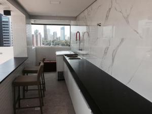 cocina blanca con encimera negra y ventana en Manaíra Apart Hotel, en João Pessoa