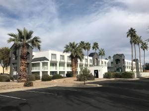 a large white building with palm trees in a parking lot at SureStay Plus Hotel by Best Western Scottsdale North in Scottsdale