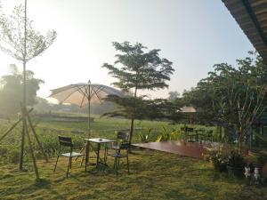 a patio with tables and chairs and an umbrella at Chill House Mae Sariang in Ban Mae Salap