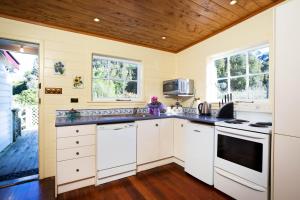 a kitchen with white cabinets and a wooden ceiling at Tairoa Lodge in Hawera