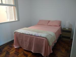a bedroom with a bed with a pink blanket on it at Quarto exclusivo em APTO compartilhado in Novo Hamburgo