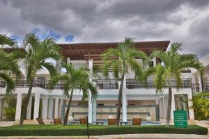 a building with palm trees in front of it at Sybaris Suites & Residences in Juan Dolio