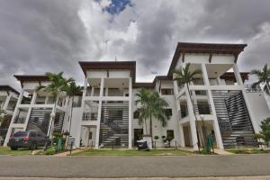 un bâtiment blanc avec des palmiers devant lui dans l'établissement Sybaris Suites & Residences, à Juan Dolio