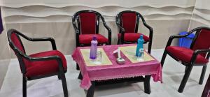 a table with four chairs and a pink table with candles at LN BEACH Homestay in Puri