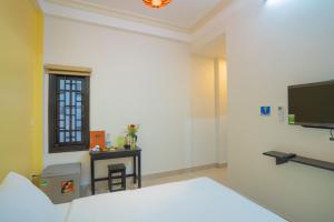 a room with a bed and a flat screen tv at Old Lane Homestay in Hoi An