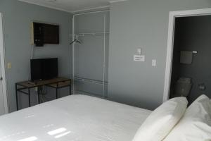 Dormitorio con cama, escritorio y TV en Aberdeen Motel, en Whycocomagh