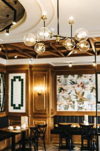 a dining room with tables and chairs and a chandelier at Hotel England Tyumen Center in Tyumen