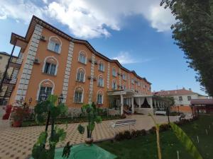 a large brick building with trees in front of it at Asia Hotel Fergana in Fergana