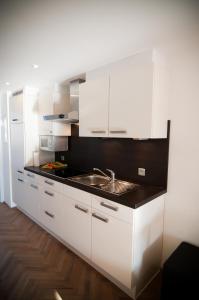 a kitchen with white cabinets and a sink at Apartment De Maasnacht in Maaseik +89 photos