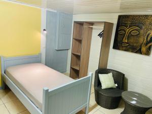 a small room with a bed and a chair at Chambres d'hôtes l'Orchidée Rose in Salazie +29 photos