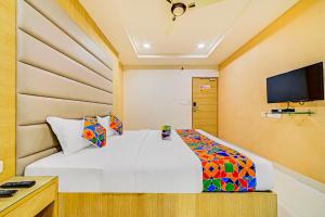 a bedroom with a white bed and a flat screen tv at FabHotel Viraj Suites Gachibowli in Hyderabad