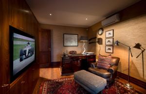 a living room with a flat screen tv and a chair at Kwandwe Fort House in Grahamstown