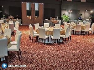 a dining room with tables and white chairs on a carpet at Desa Selatan Resort Pengerang in Pengerang