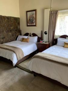 a bedroom with two beds and a stone wall at Mants’ebo Guest House Mokhotlong in Mokhotlong