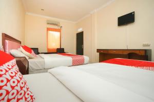 a hotel room with three beds and a flat screen tv at OYO 2003 Female Guest House in Probolinggo