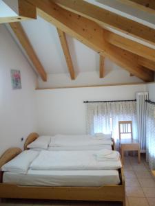 a bedroom with four beds in a room with wooden ceilings at Taxus Hostel in Pieve Tesino