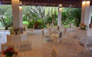 un patio con mesas blancas, sillas y flores en Eva Lanka Hotel - Beach & Wellness, en Tangalle
