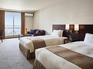 a hotel room with two beds and a window at Cypress Resort Kumejima in Kumejima