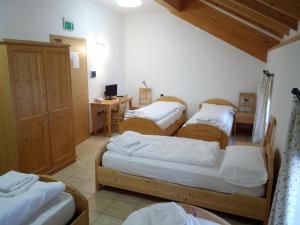 pokój z czterema łóżkami i biurkiem z komputerem w obiekcie Taxus Hostel w mieście Pieve Tesino