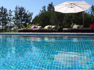 a swimming pool with chairs and an umbrella at Casas Dos Infantes - Turismo Rural in Caldas da Rainha