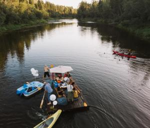 un grupo de personas en un barco en un río en Camping Jaunzāģeri, en Inciems