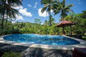 a swimming pool in a resort with palm trees in the background at Villa Uma Ayu Sidemen in Sidemen