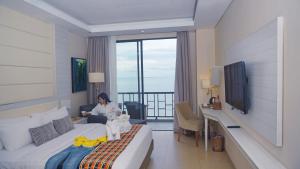 古邦的住宿－Sotis Hotel Kupang，坐在酒店房间床上的女人