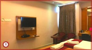 a hotel room with a bed and a flat screen tv at Hotel RAKS in Thanjāvūr