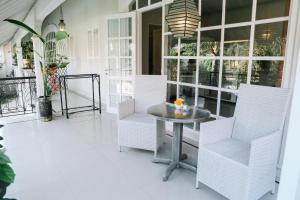 porche con sillas blancas, mesa y ventanas en Casa Artista By Kresna Hospitality, en Seminyak