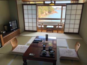 a room with a table and chairs and a view of the water at Hotel Nagisaya in Katsuura