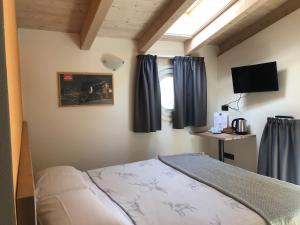 a bedroom with a bed with blue curtains and a television at Marzia Lounge in Bormio