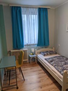 a bedroom with two beds and a desk and a window at Ruhrtropolis Hostel in Essen