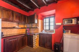 a kitchen with wooden cabinets and a red wall at Casa Amoreira - Quinta Amoreira in Faro