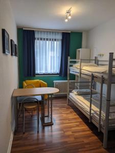 Zimmer mit 2 Etagenbetten, einem Tisch und einem Stuhl in der Unterkunft Ruhrtropolis Hostel in Essen