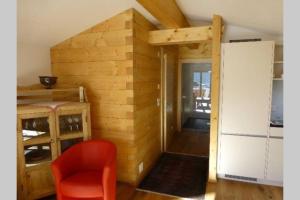 Zimmer mit einer Holzwand und einem roten Stuhl in der Unterkunft Casa Ual / Capaul in Laax