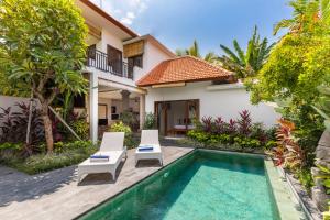 a villa with a swimming pool and two chairs and a house at Sawah Villas in Ubud