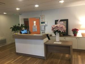 a lobby with a reception desk with flowers on a counter at Hôtel Motelia in Moissy-Cramayel