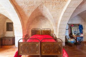 a bedroom with a bed with red sheets in a stone wall at Casa Leo in Carovigno