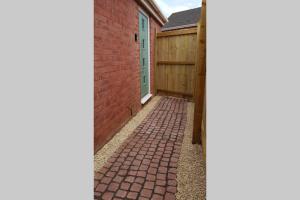 una pasarela de ladrillo que conduce a una casa con una valla de madera en Annex in Chippenham with Parking and WIFI, en Chippenham