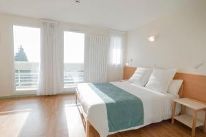 a bedroom with a large white bed and large windows at Centre Jean XXIII in Annecy