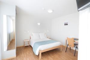 a white bedroom with a bed and a desk at Centre Jean XXIII in Annecy